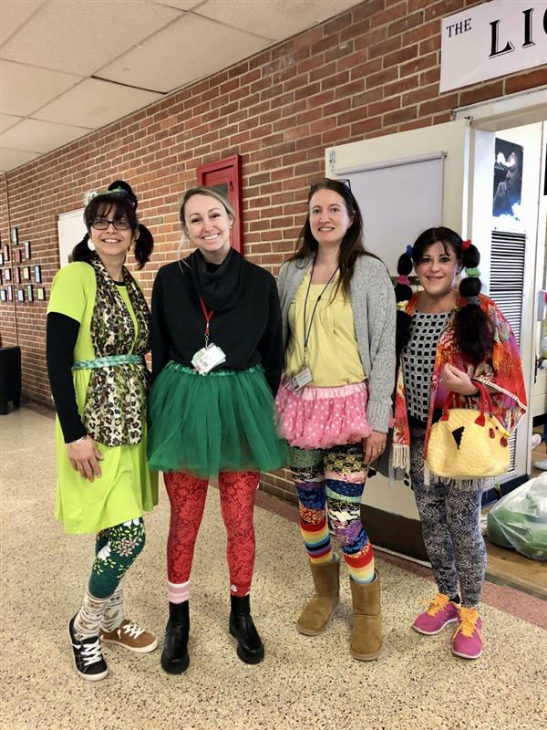 Four women in vibrant costumes smiling for a photo.