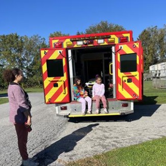 Children standing in front of ambulance.