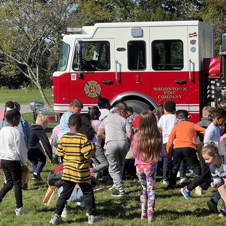 Kids playing near a fire truck on green grass.