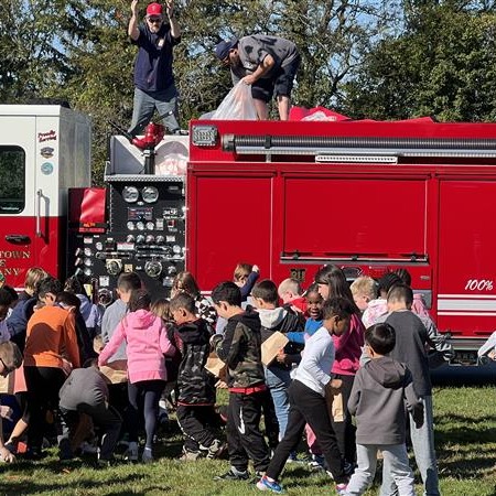 Kids playing near a fire truck on green grass.