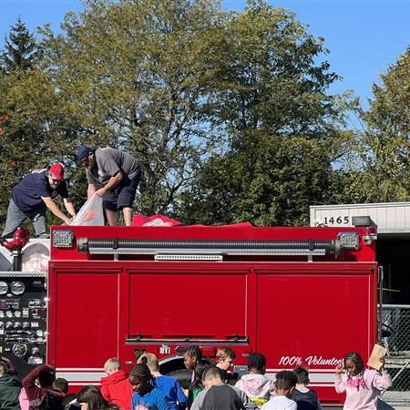 Kids playing near a fire truck on green grass.