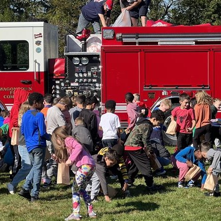 Kids playing near a fire truck on green grass.