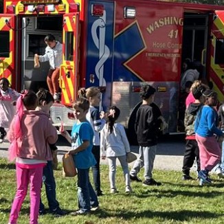 Kids playing near a fire truck on green grass.