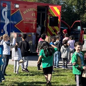 Kids playing near a fire truck on green grass.