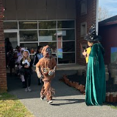 Kids in costumes walking on sidewalk.