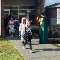 Kids in costumes walking on sidewalk.