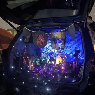 Car with festive trunk decorations and colorful lights.