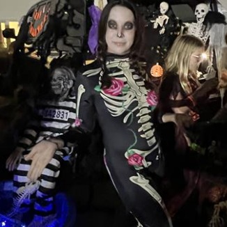 Woman in skeleton costume poses in front of crowd.