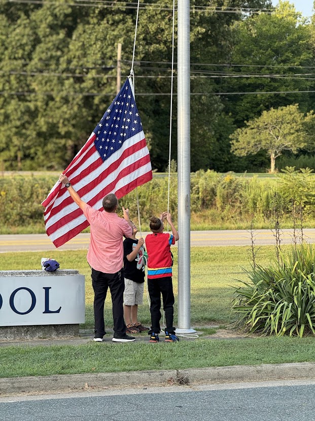 Students and teacher putting up the American flag