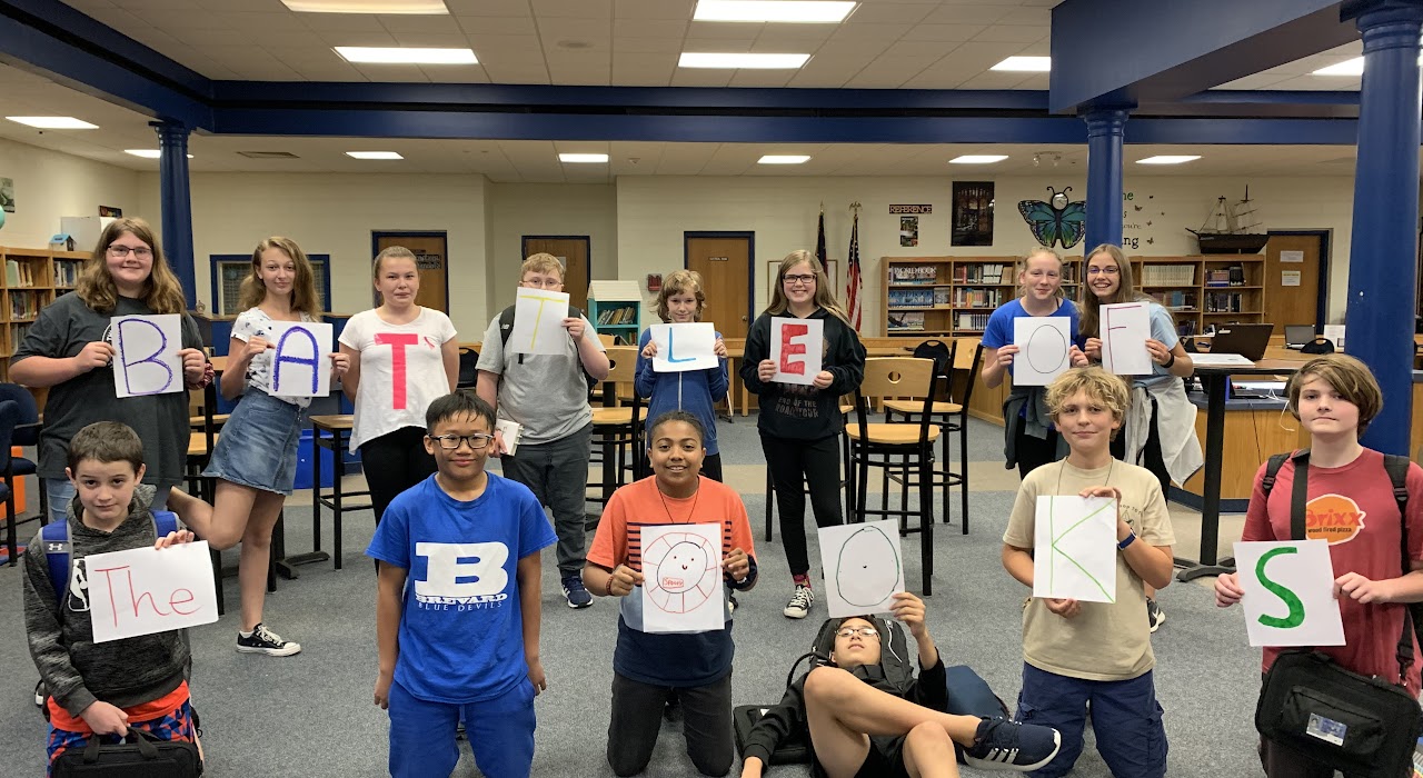 kids in classroom holding up battle of the books signs 