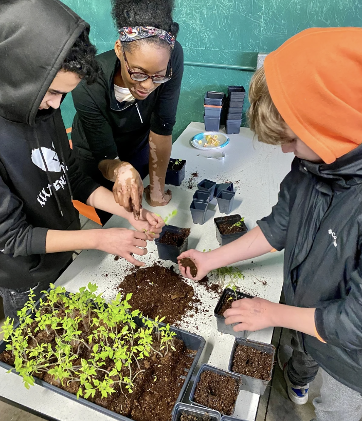 two learners planting seeds with a gardner