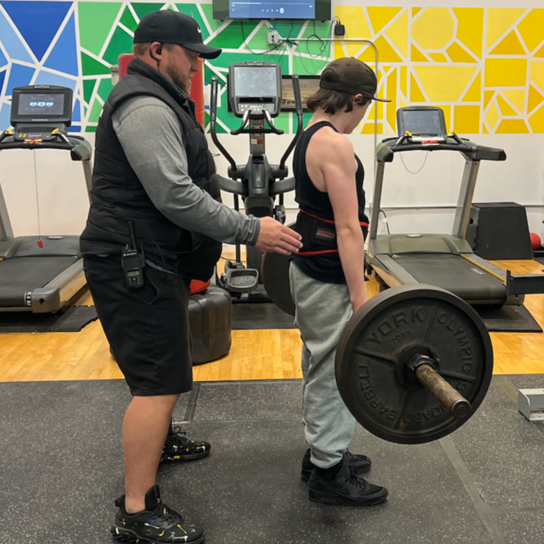 young learner lifting weights with staff support