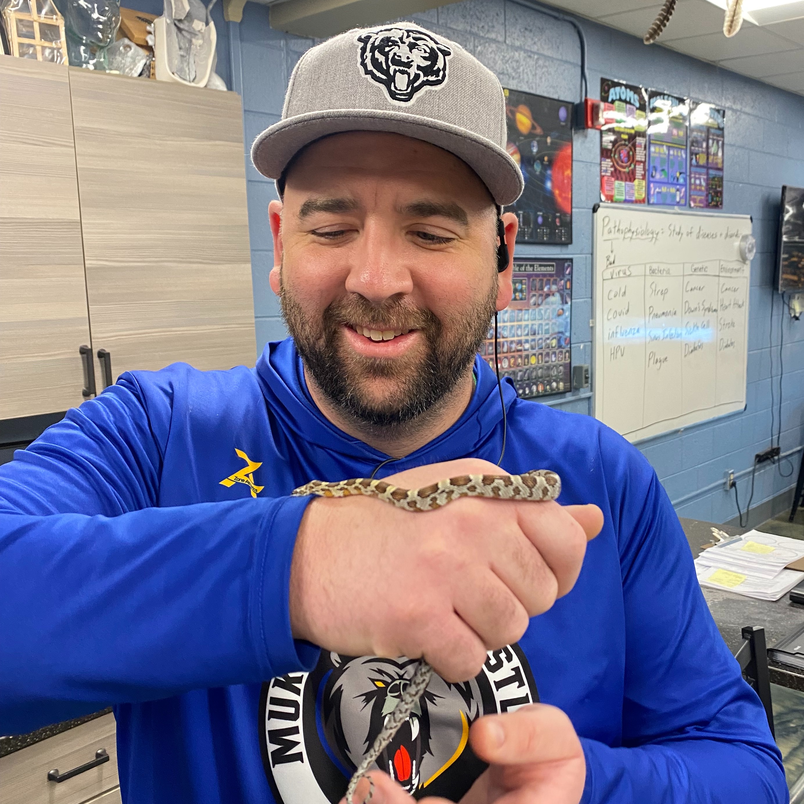 male educator with small snake in classroom