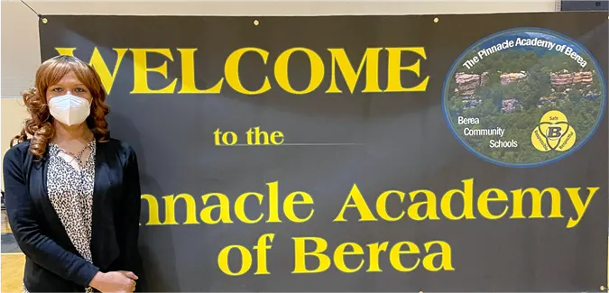 Woman stating in front of a sign saying Welcome to the Pinnacle Academy of Berea