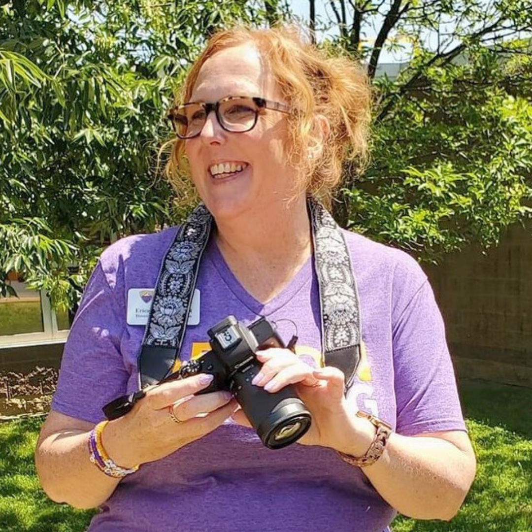 Woman in purple shirt holding a camera