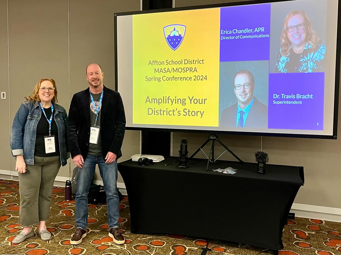 Erica Chandler, APR, with Dr. Travis Bracht, superintendent, stand in front a screen ready to present at the 2024 MASA/MOSPRA conference