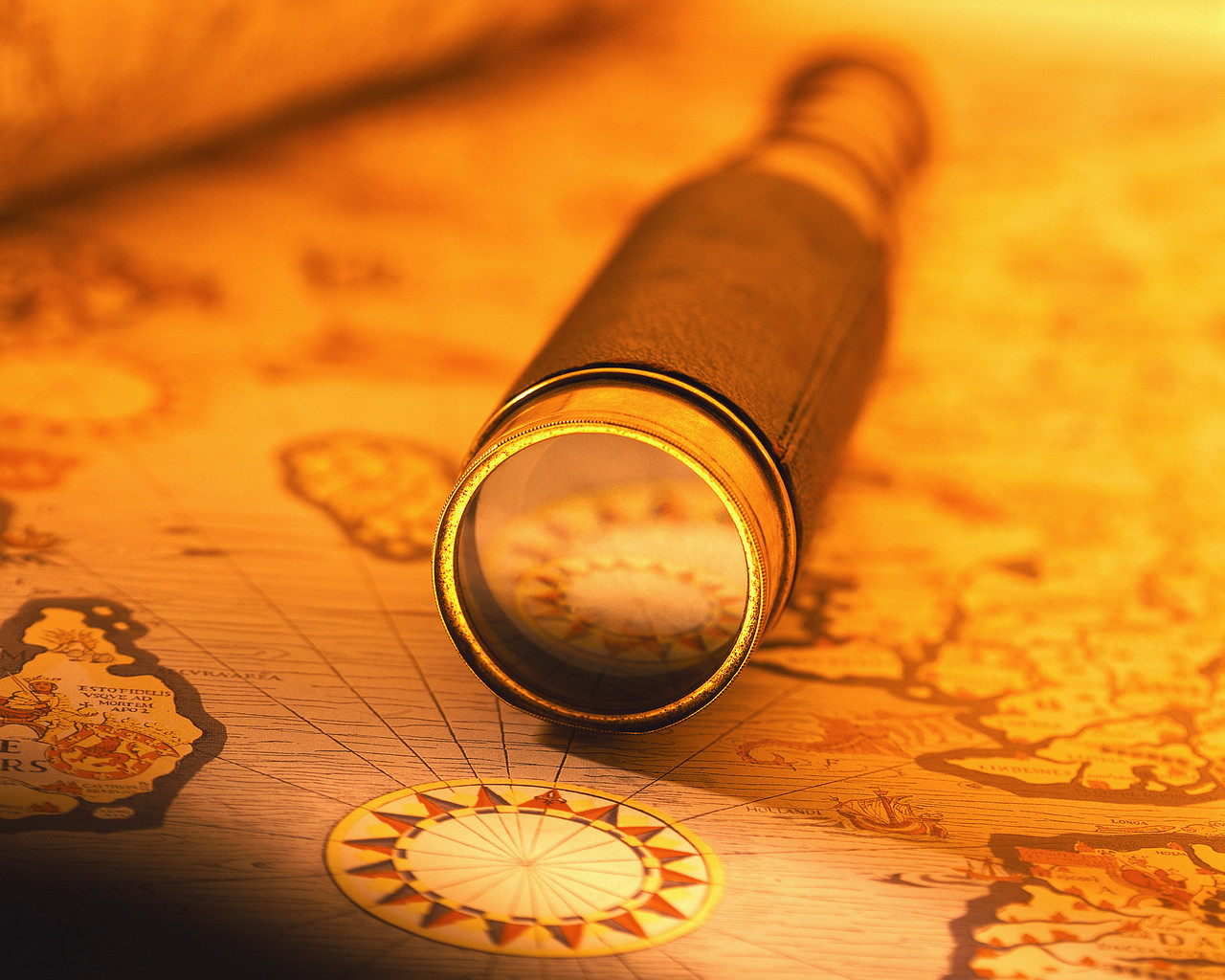 A magnifying glass rests on an ancient map, highlighting intricate details of the cartographic design.