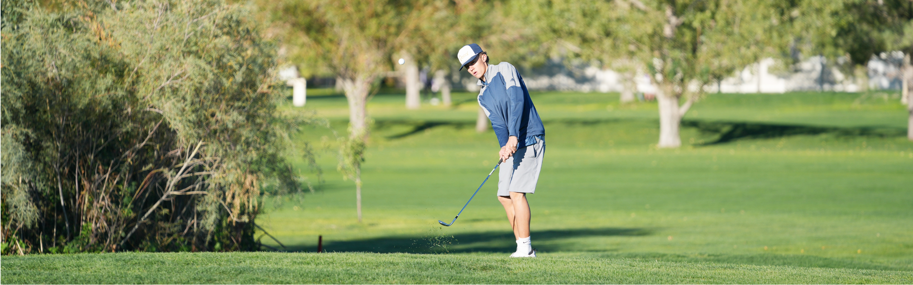student hitting a golf ball at tournament