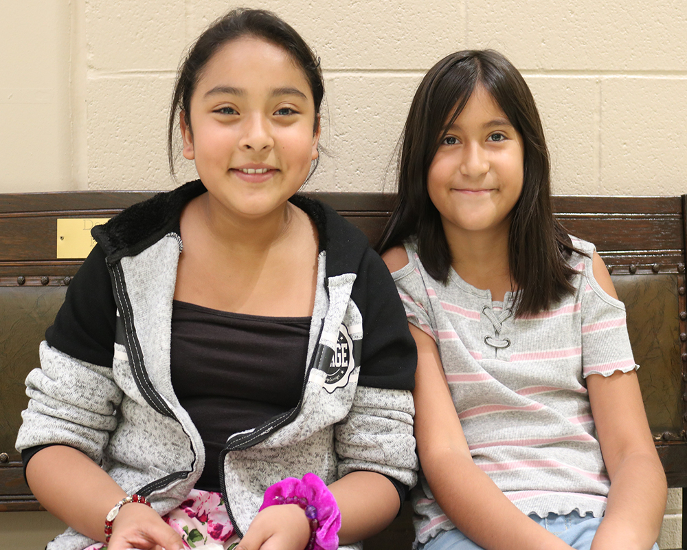 Two individuals, possibly friends or siblings, posing on a bench.