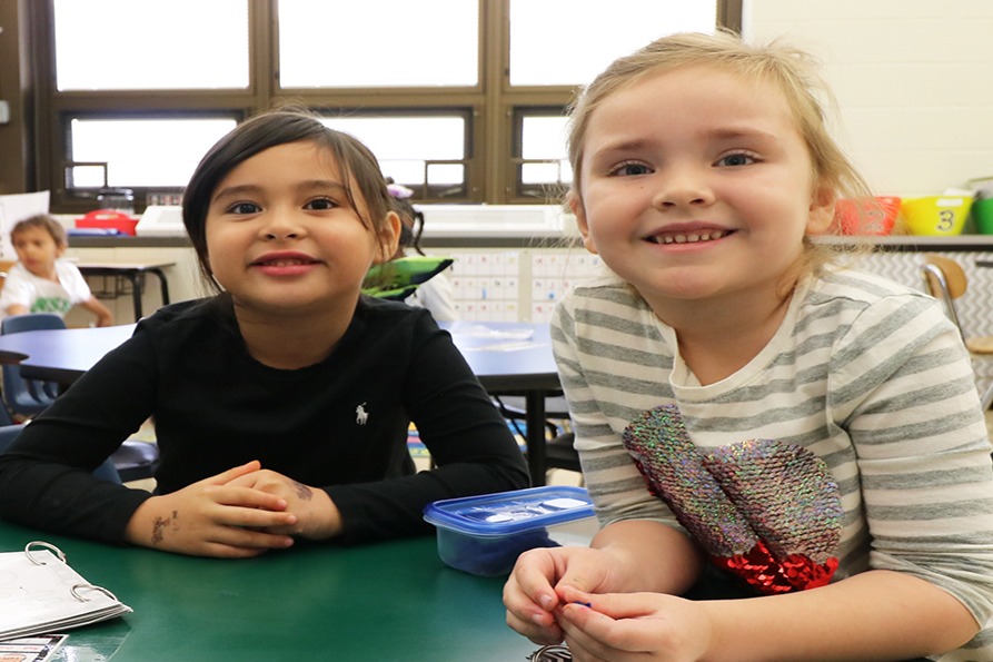 Two children posing at a school desk.