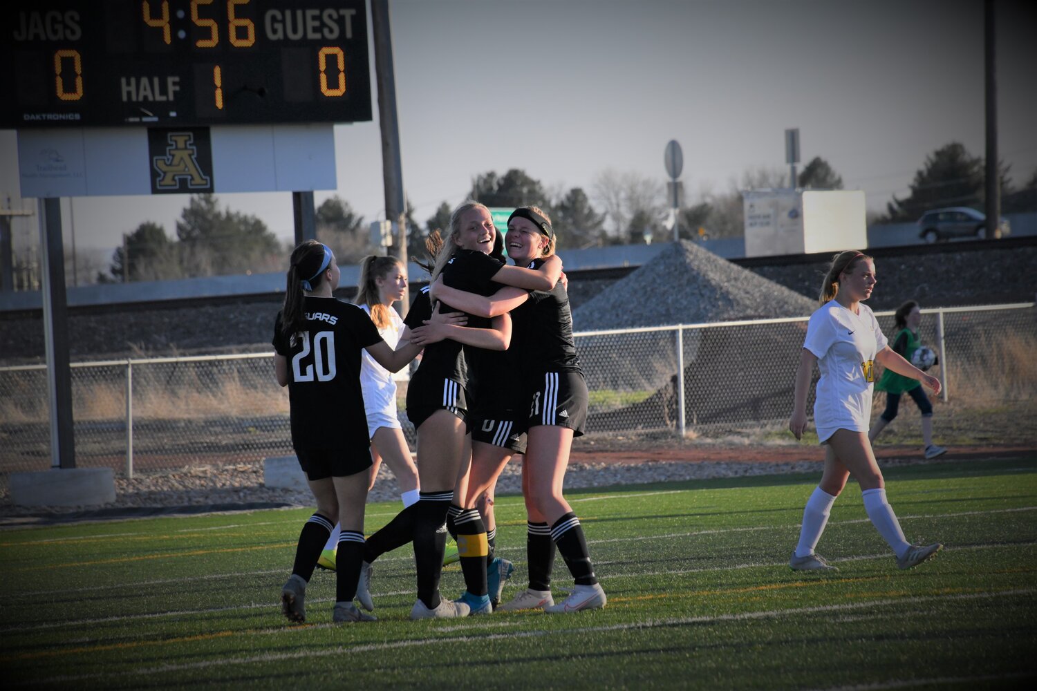 A group of girls celebrate a goal on the soccer field.