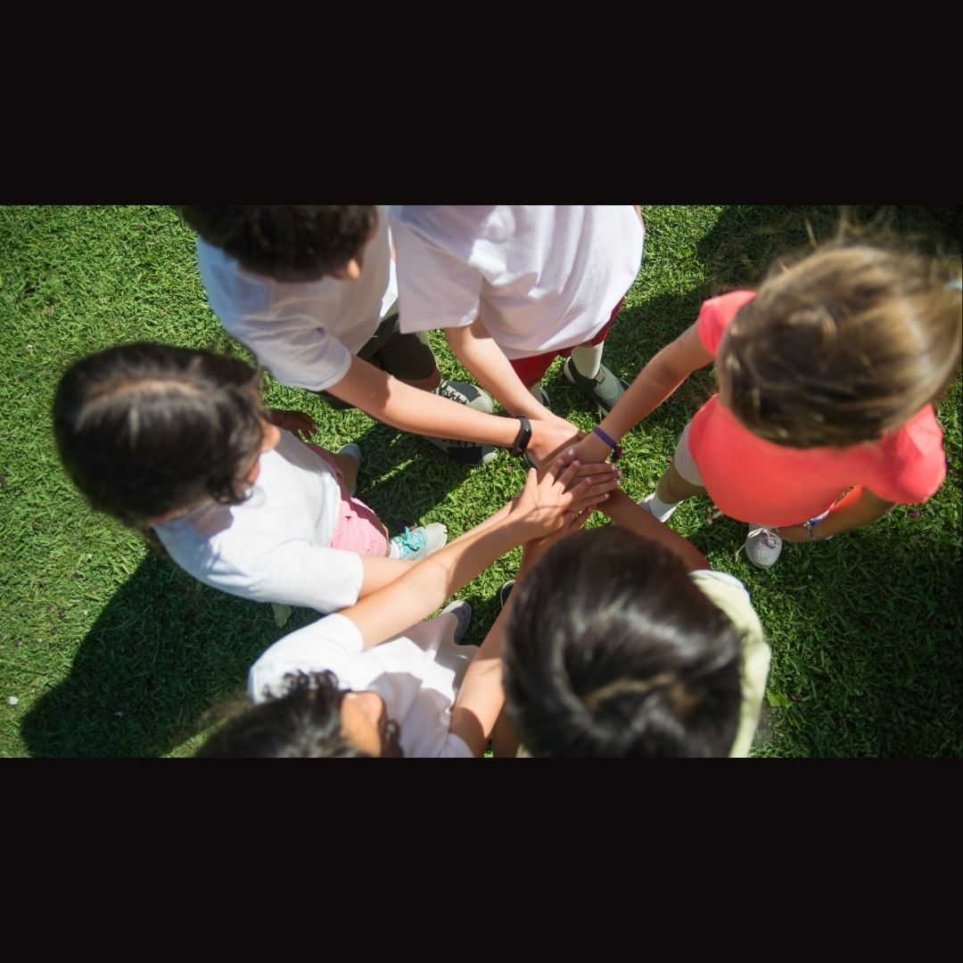 kids in circle with hands in center