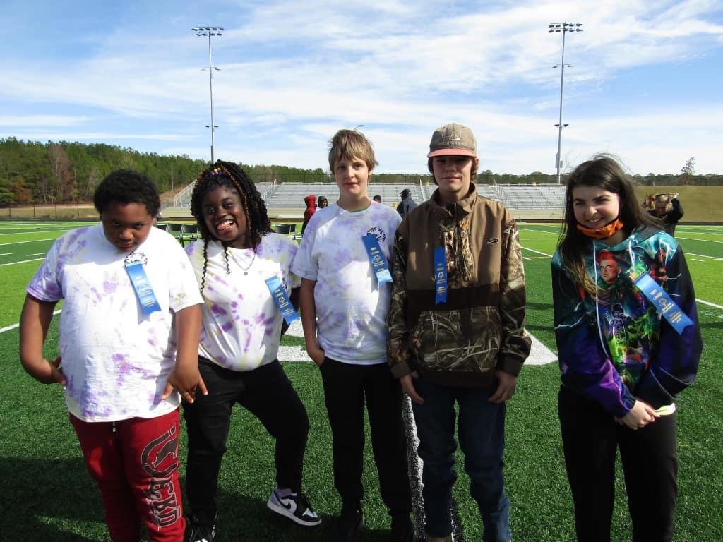 Five people posing for a photo at an outdoor event.