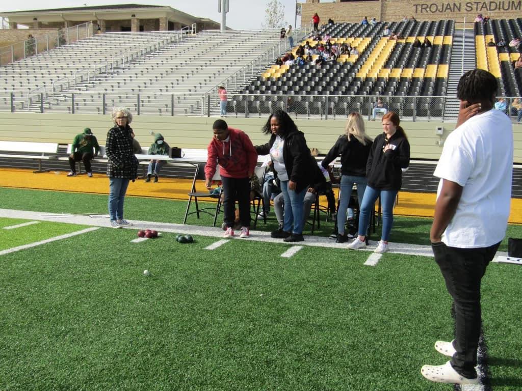 A group of people participating in a frisbee game on a football field.