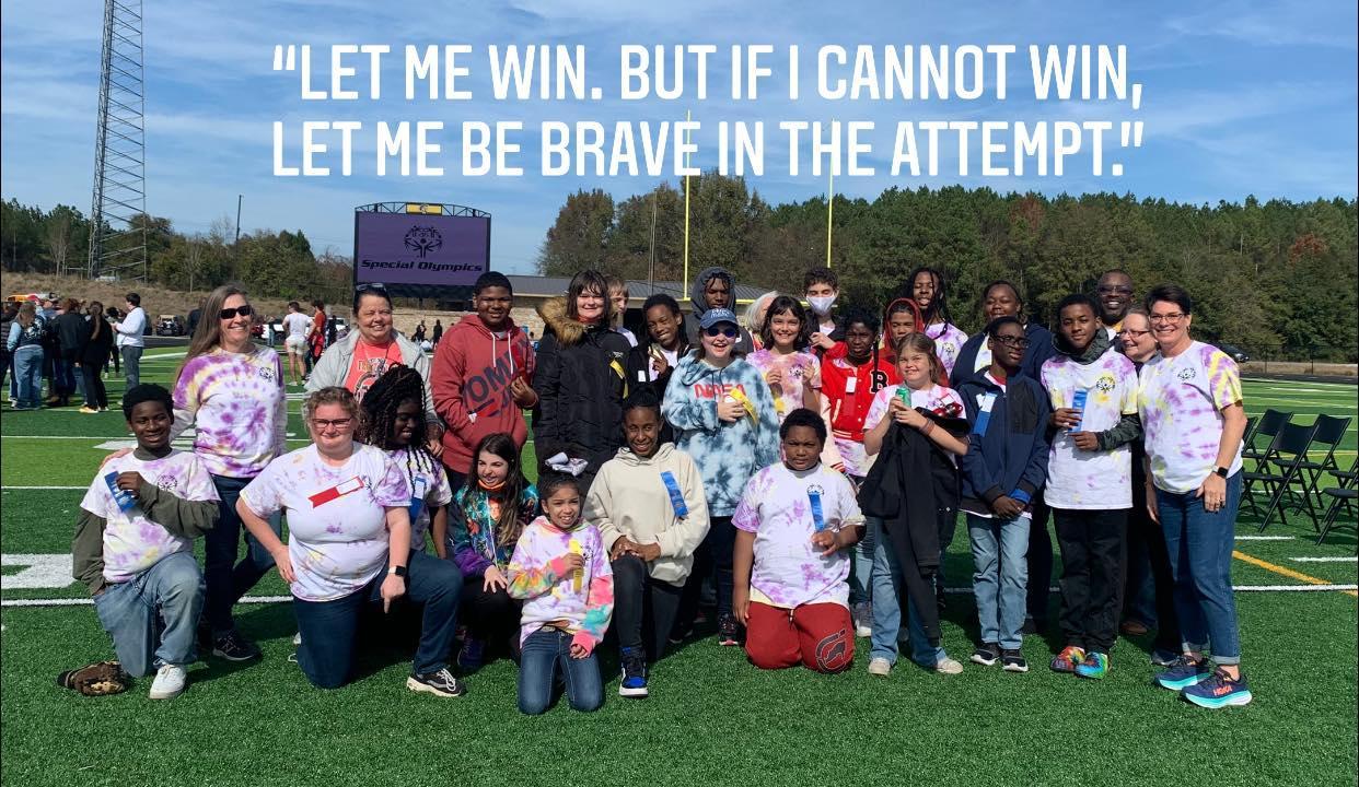 A group of people, likely a school team or sports event participants, posing for a photo with a humorous quote overlaid.