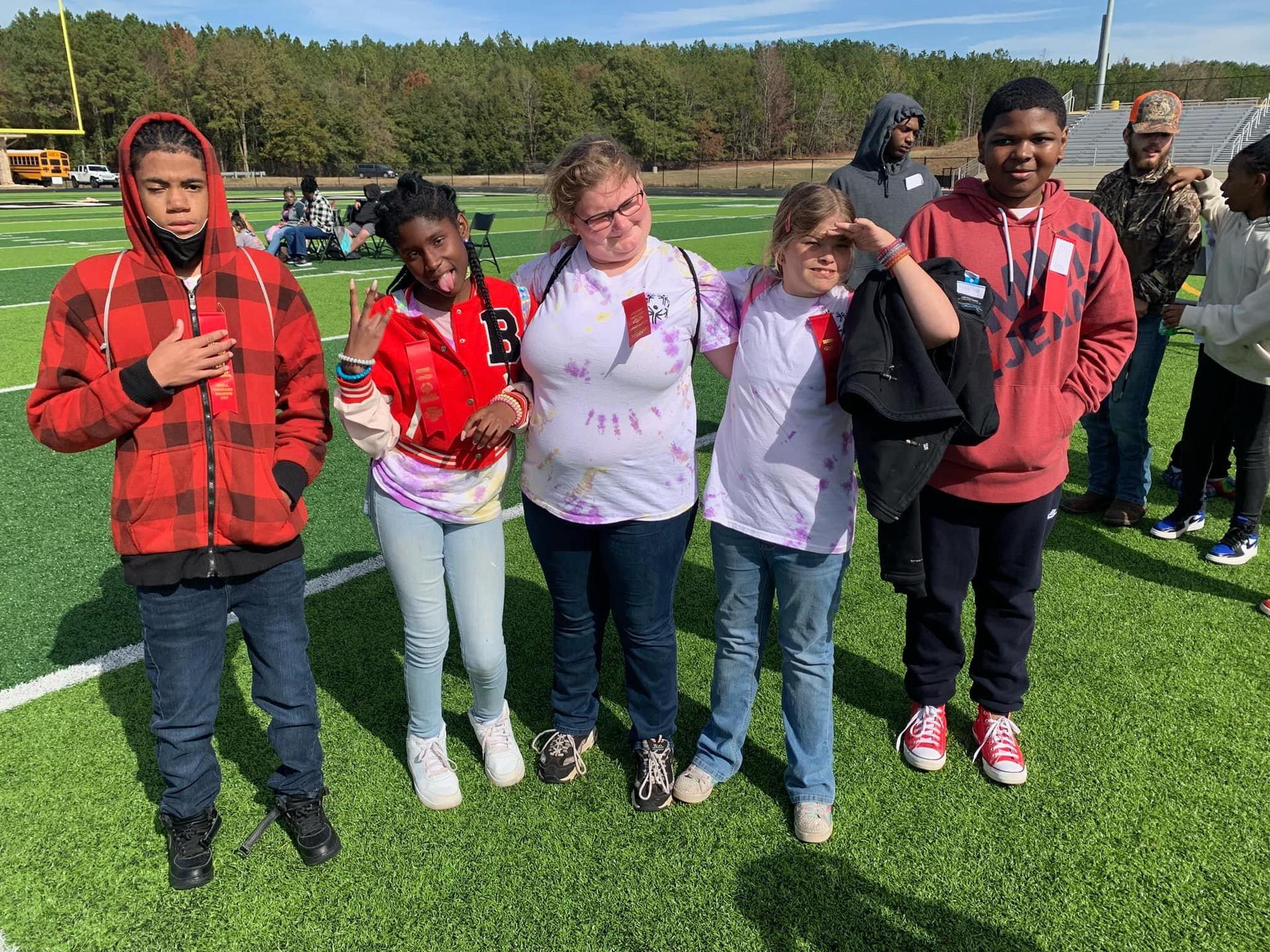 Friends posing for a photo on a football field.