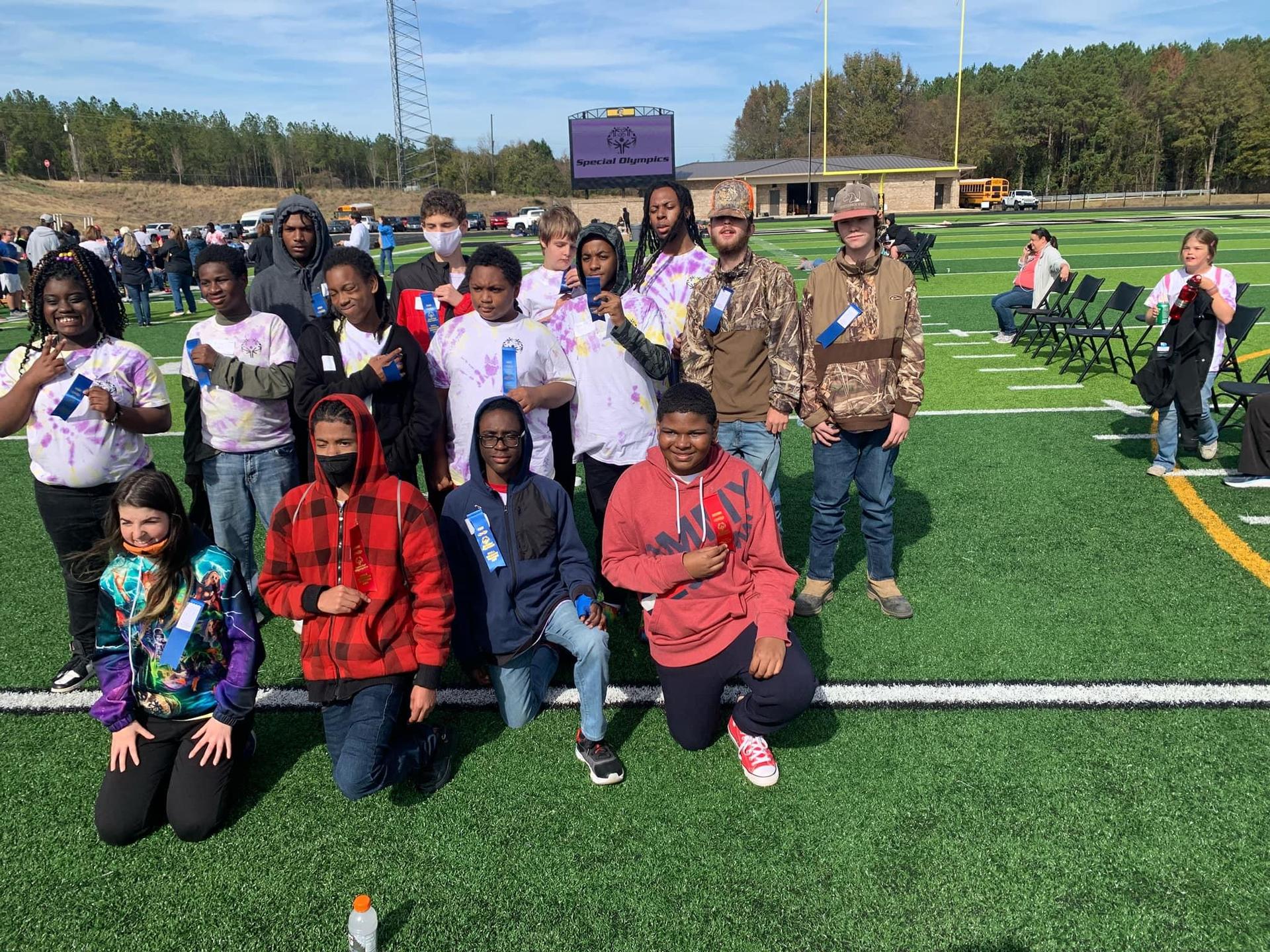 A group of people, including kids, gathered for an event at a stadium, proudly showing their colorful hands, likely to signify participation or achievement in the event.