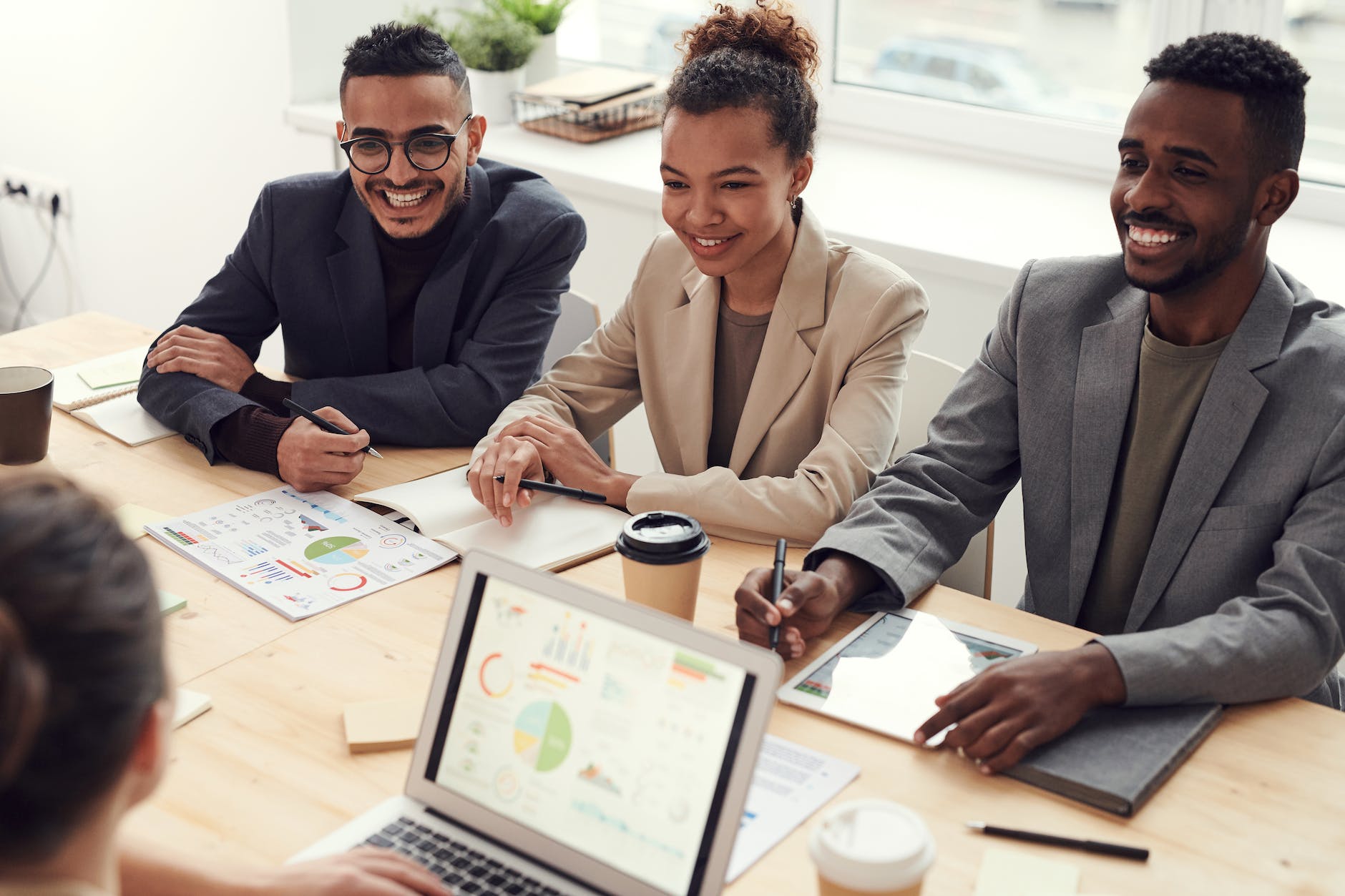 three people smiling while having a meeting