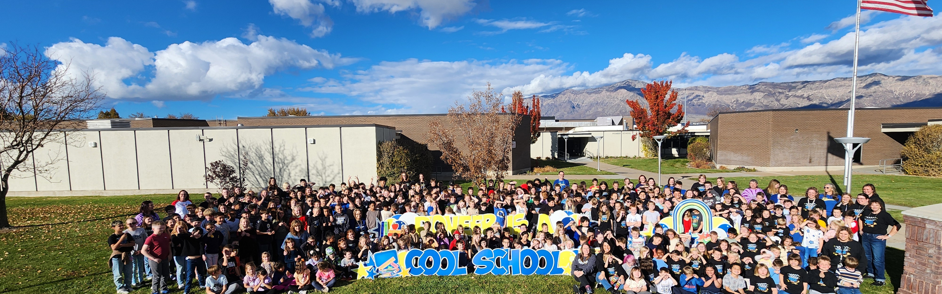 Teachers and Students posing for the camera in front of the school