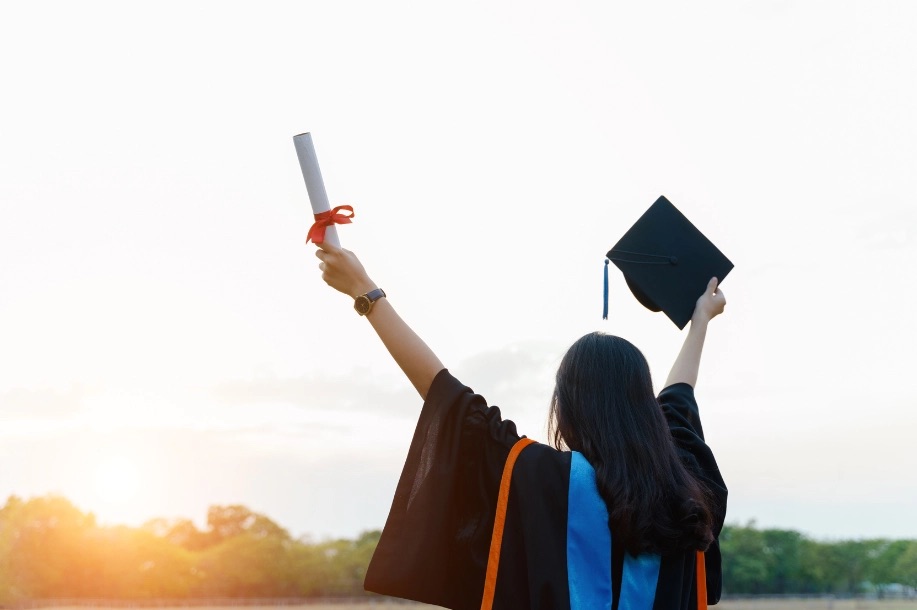 studnet holding a diploma and graduation hat 