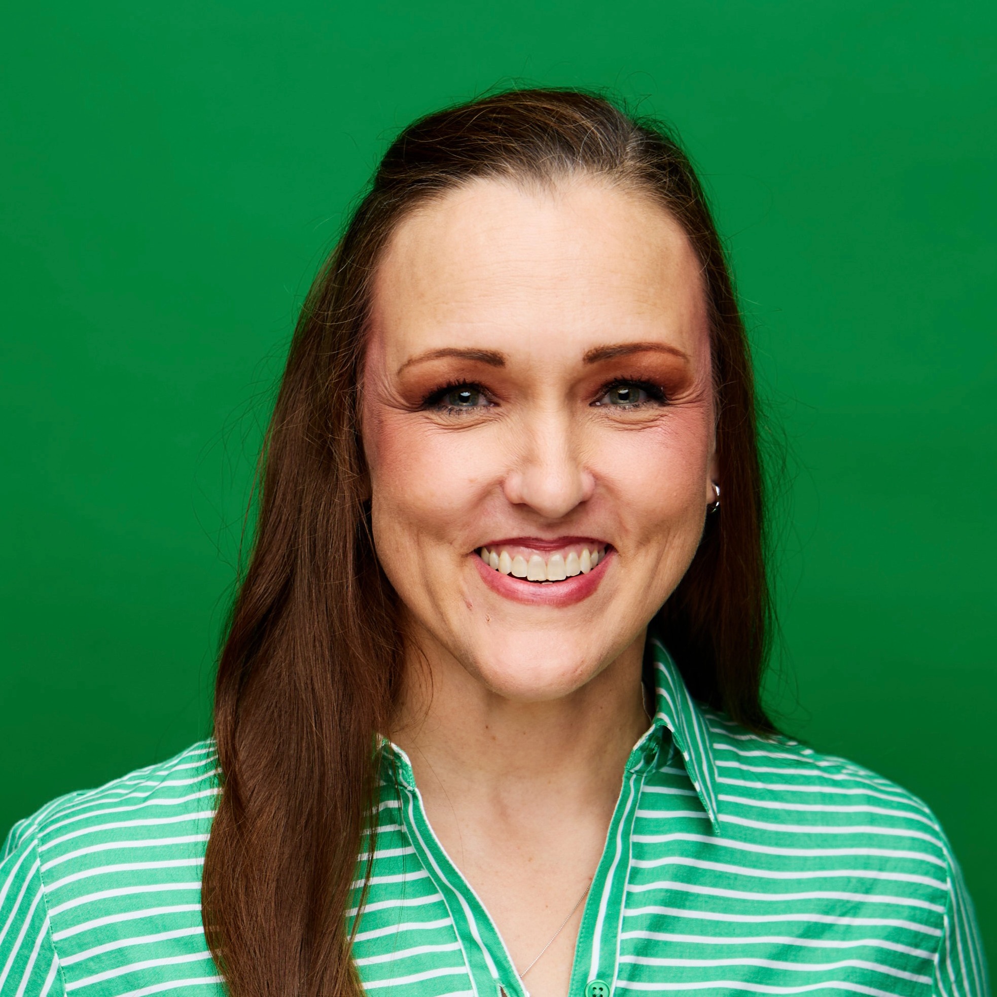 Teacher smiling in a green dress against a green background