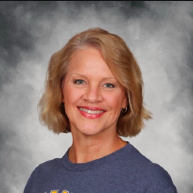 Teacher smiling against a gray background