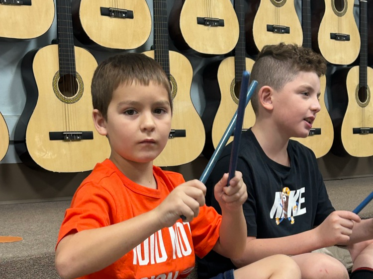 Children learning to use drum sticks in music class