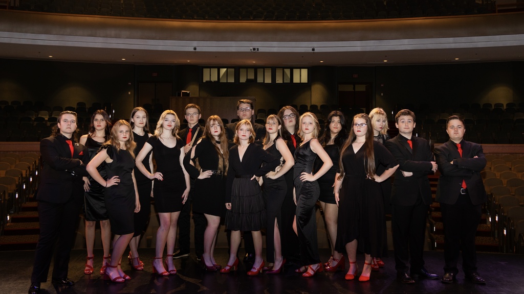 A group of high school choir students dressed in black, and the girls are wearing red shoes