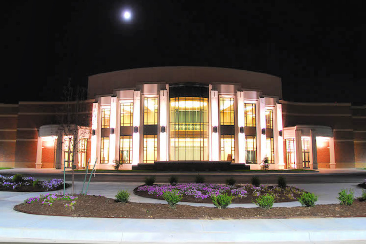 Front exterior of the Robson Performing Arts Center in Claremore, OK at night. The building is lit up from interior and exterior lights.