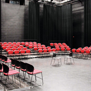 View of the Black Box Theatre with red chairs set up for audience viewing