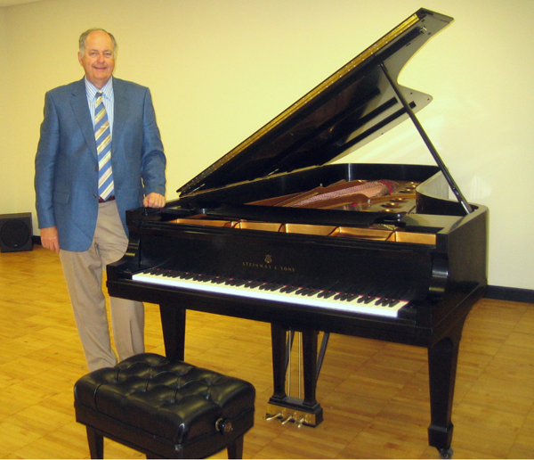 Jerry Hastings standing next to the Steinway Concert Grand Piano that has been donated to the Robson Performing Arts Center