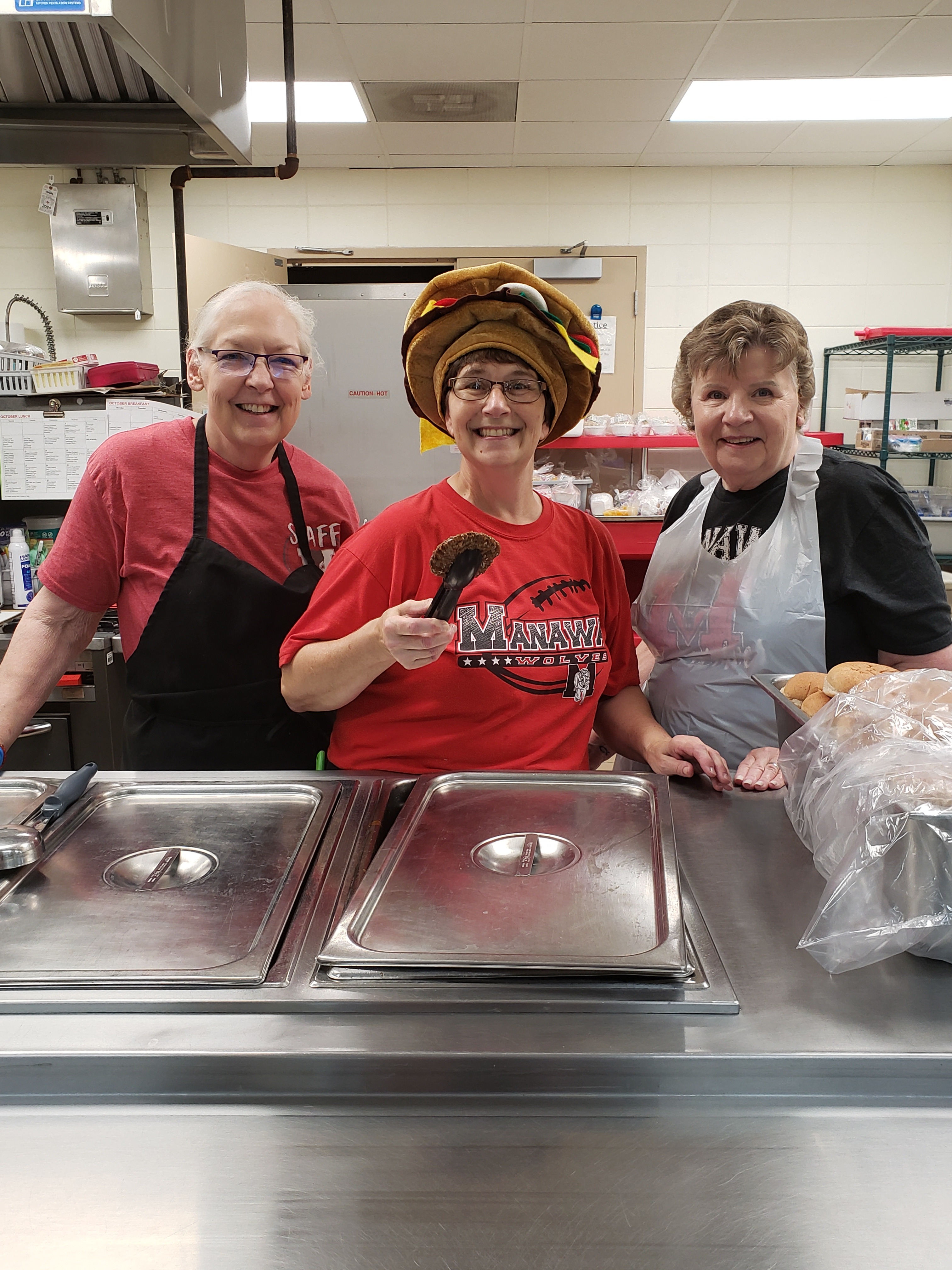 Lunch ladies on burger day wearing a burger hat and posing for picture 