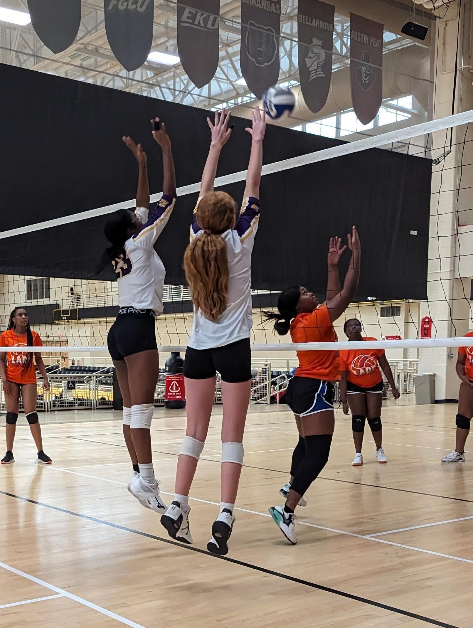 two volleyball girls jumping to hit the ball