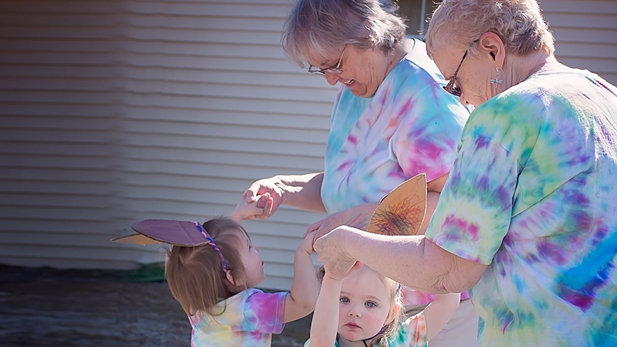 A woman smiling with two children standing beside her, all looking happy and content.