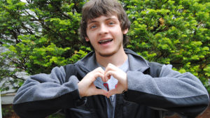 A young man making a heart with his hands