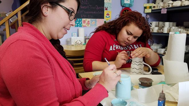  A couple of women sitting at a table working on something