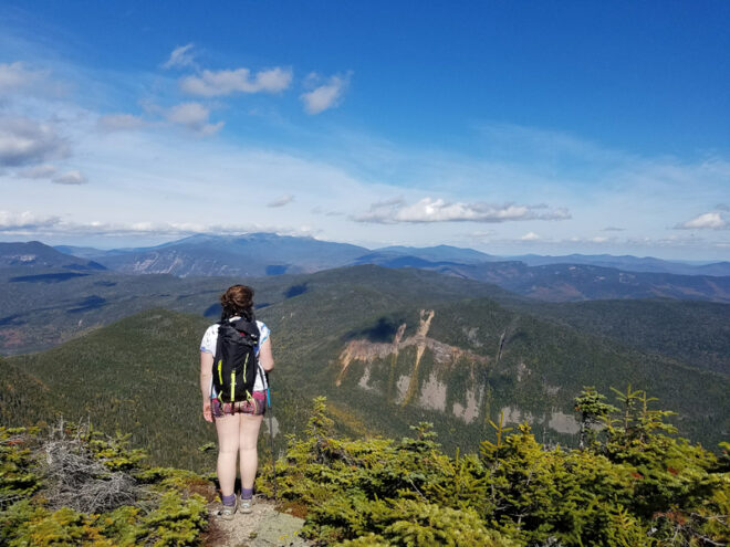 A person with a backpack standing on top of a mountain