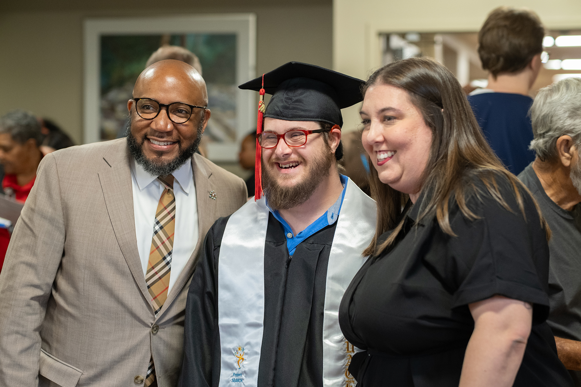 Dr. Anthony Lewis taking photo with graduating student and their mom