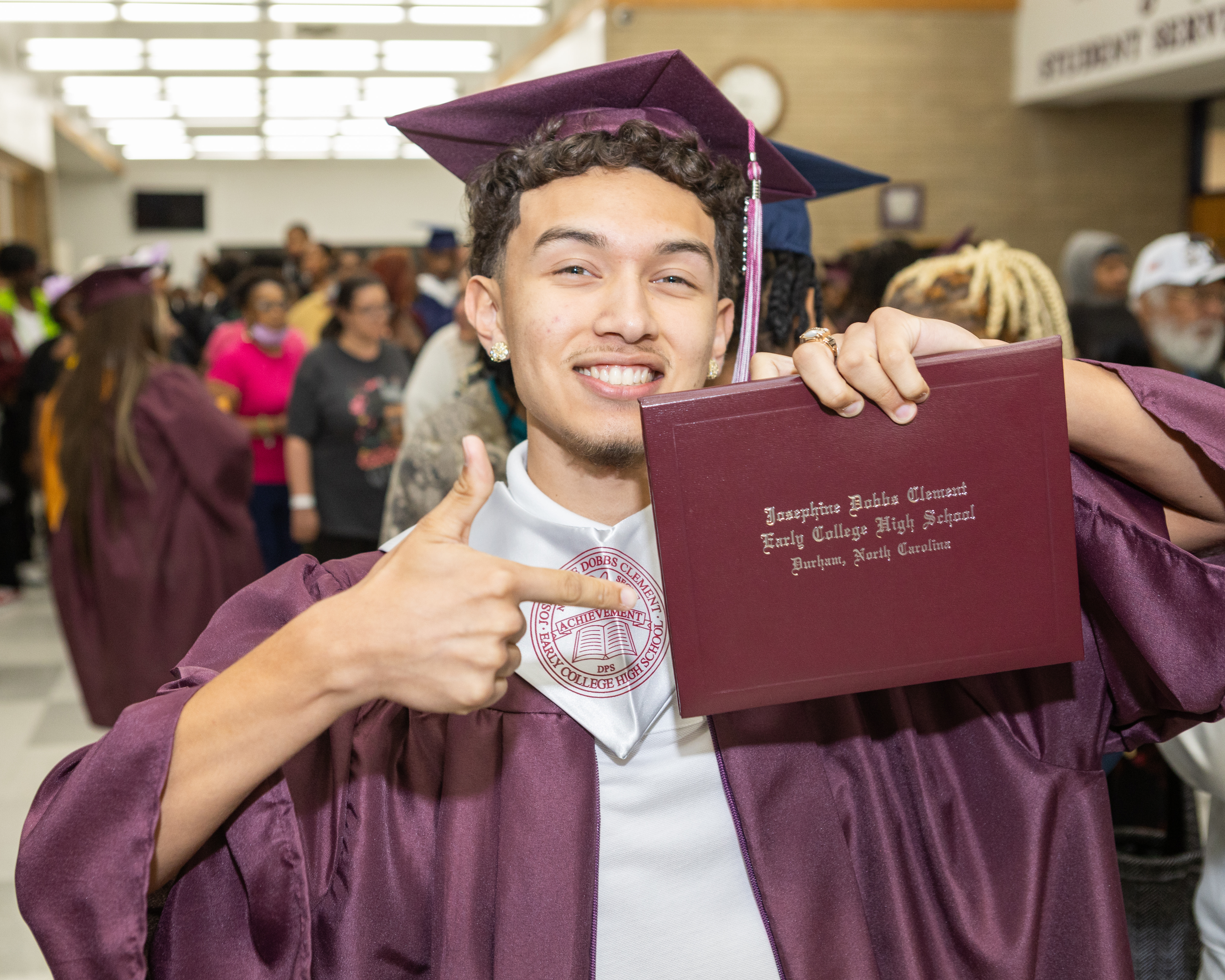 Student in cap and gown holding diploma cover