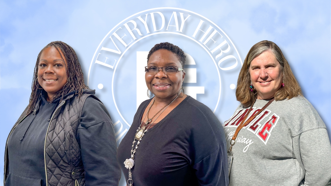 Three women stand together smiling in front of a holiday backdrop with snowflakes and festive lights. From left to right: Latorsha Bryant, Lakeisha Pigatt, and Paula Huggins.